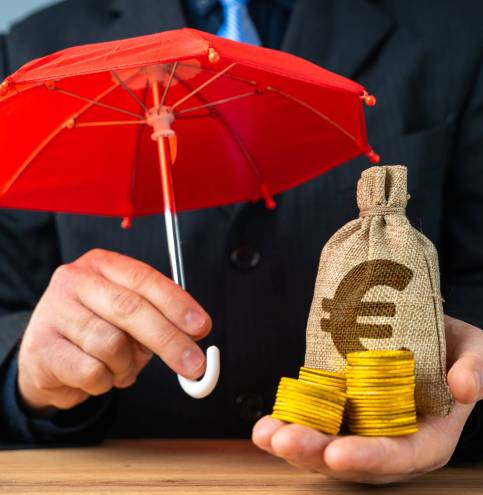 Businessman holding euro money bag with coins under red umbrella. Capital preservation. Savings and deposits insurance concept.
